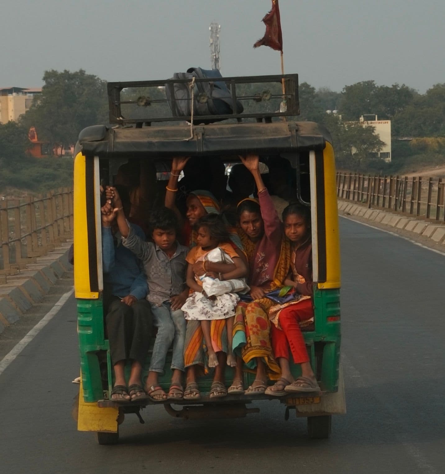 Passengers riding an auto rickshaw on a highway, India